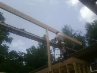 Carpenter setting a ridge beam over a new addition frame — Ice Dam Removal by Roofing Brothers in Manchester