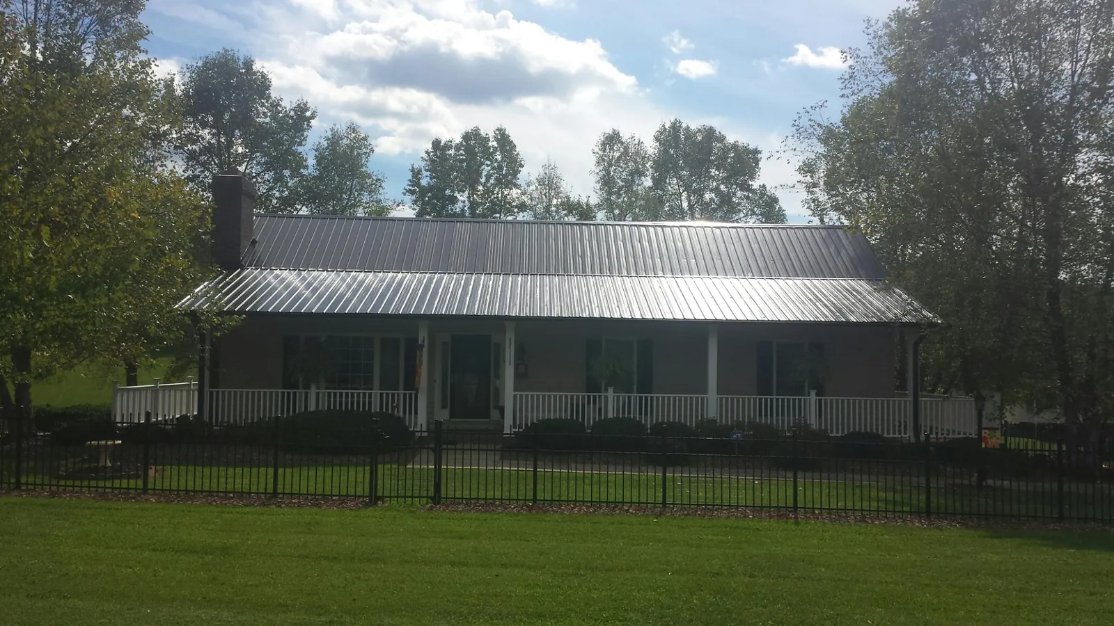Gray metal roof on a brick ranch with a full width front porch — Gutter Guard Installation work by our crew in Manchester